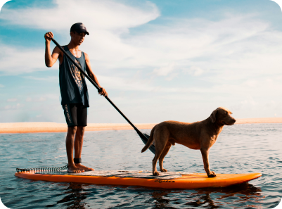 Picture of one person with a dog on an organge paddle board on a lake
